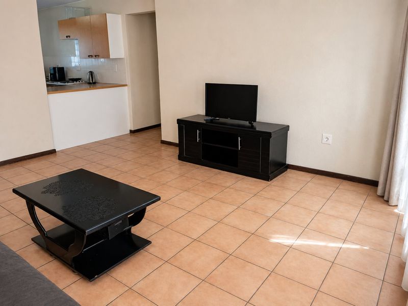Open plan living area featuring tiled flooring and a functional kitchen space with built-in cabinetry and countertops.