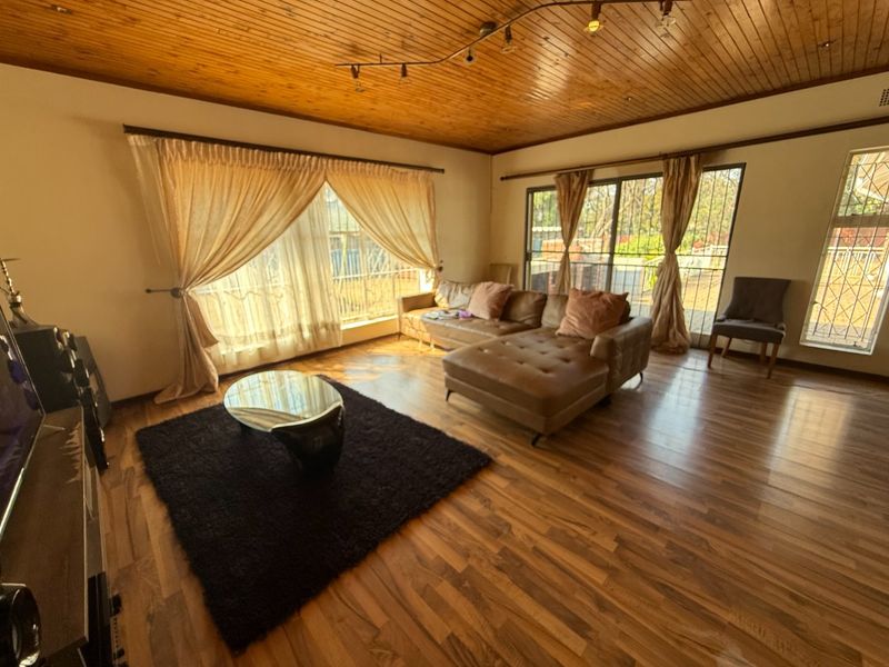 Spacious living room featuring warm timber ceilings, laminate flooring, and large sliding glass doors that provide ample natural light and access to the outdoors.