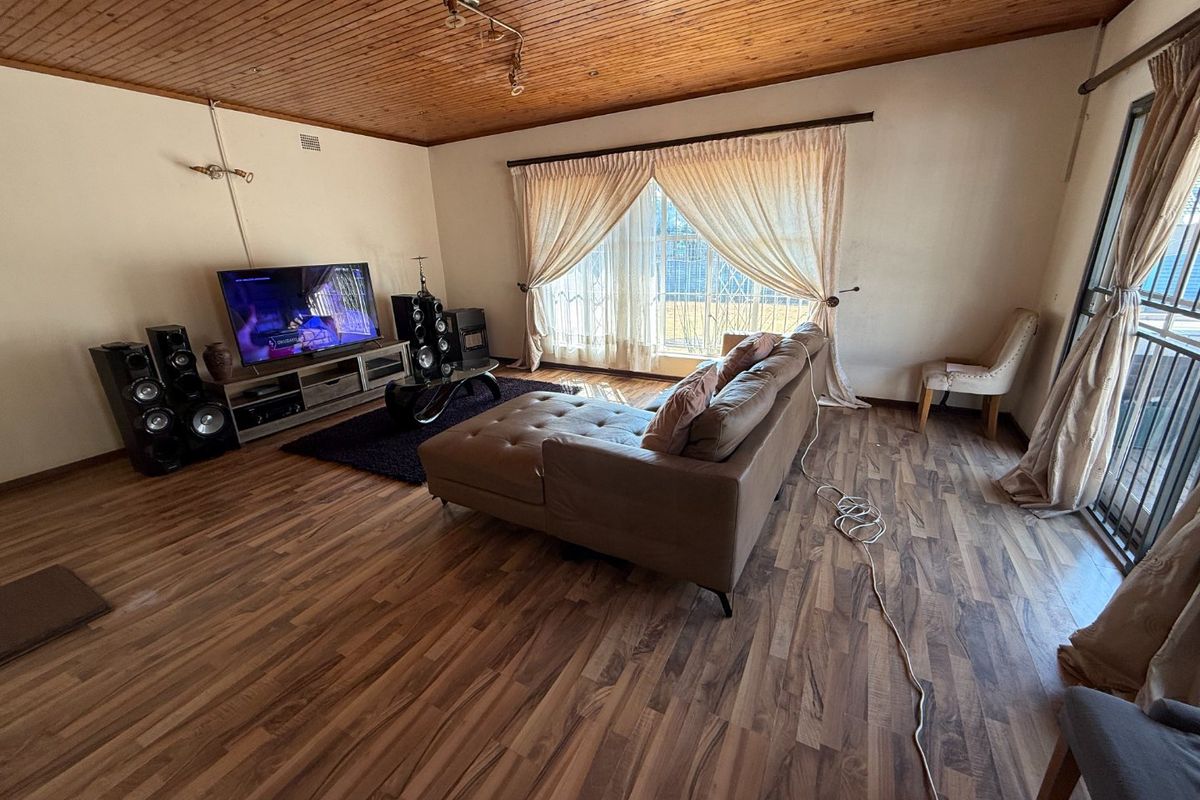 Spacious living room featuring warm timber-clad ceilings, laminate flooring, and large sliding glass doors that provide access to the exterior.