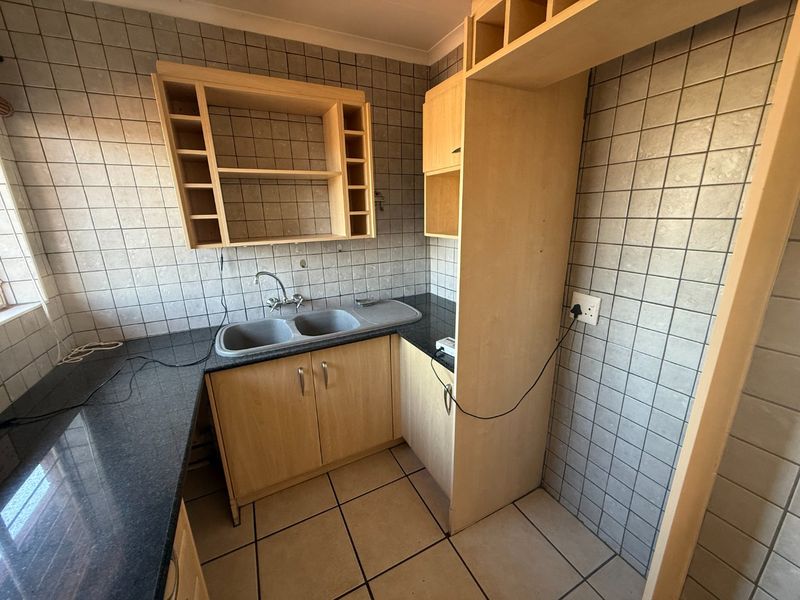 A functional kitchen area featuring granite countertops, a double basin sink, and light wood cabinetry with ample built-in storage space.