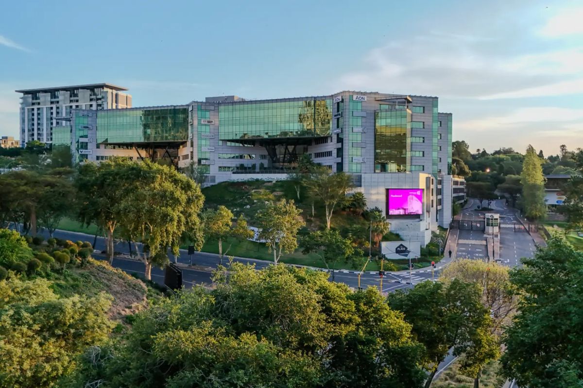 Aerial view of a modern commercial office complex featuring glass facade architecture, landscaped surroundings, and integrated digital signage.
