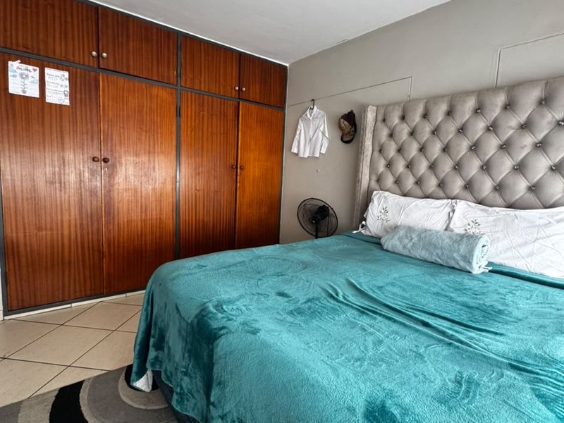 A bedroom featuring a large built-in wooden wardrobe and tiled flooring, offering functional storage space.