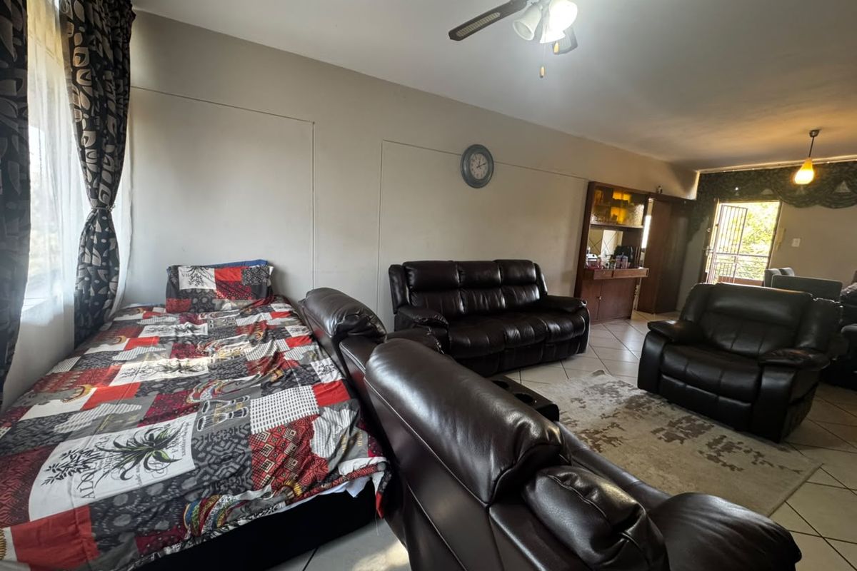 Spacious living area featuring ceramic floor tiles, a ceiling fan, and a built-in display cabinet, with direct access to an outdoor area.