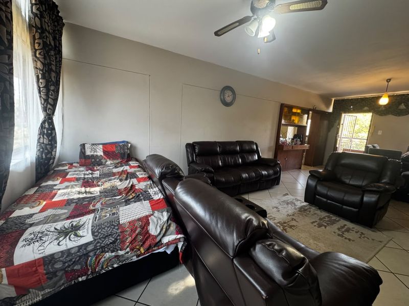 Spacious living area featuring ceramic floor tiles, a ceiling fan, and a built-in display cabinet, with direct access to an outdoor area.