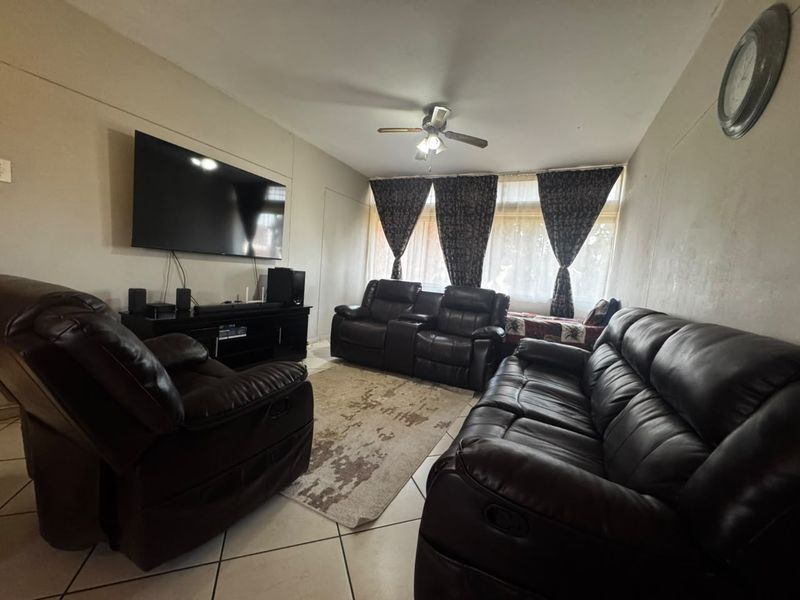 A living room featuring tiled flooring and a ceiling fan, providing a functional space for relaxation.