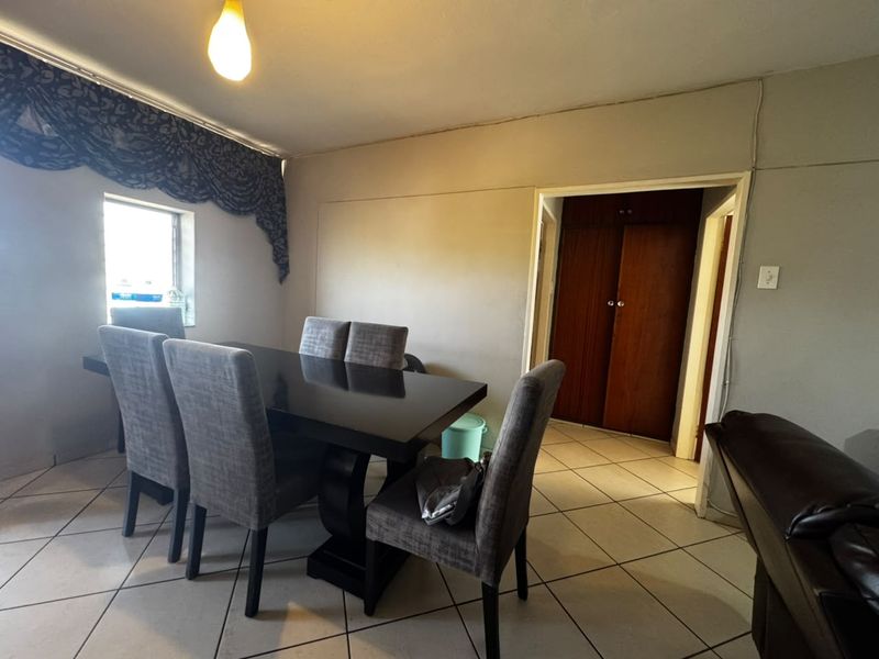 Dining area featuring tiled flooring and built-in storage cupboards, providing a functional space for meals with direct access to adjacent rooms.