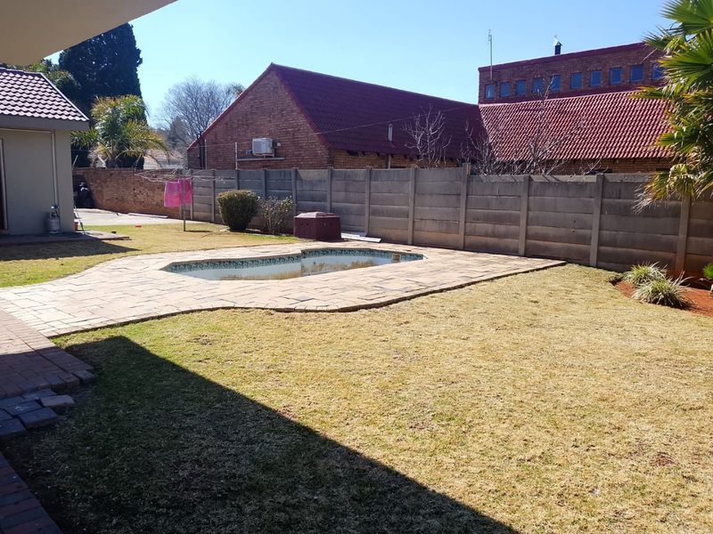 Rear garden featuring a swimming pool with paved surround and precast concrete boundary walling.