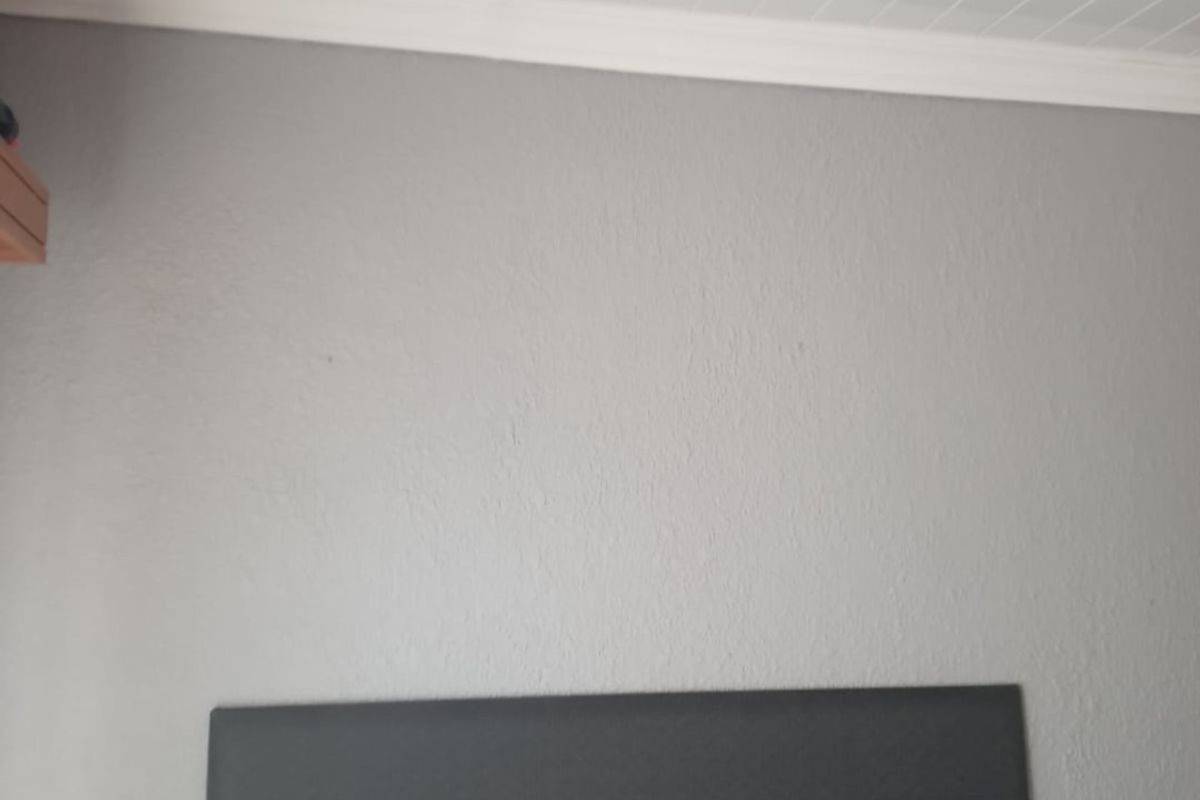 A bedroom interior featuring a grey wall with a tongue and groove ceiling and crown molding.