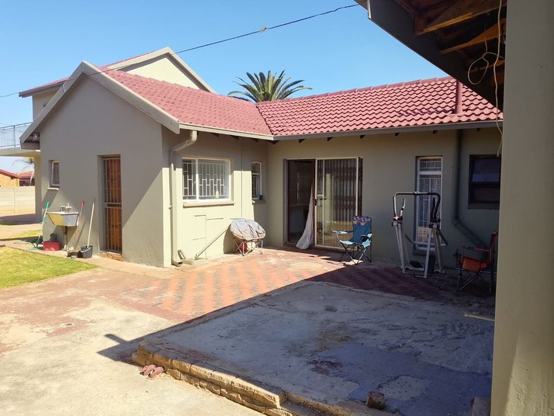 Rear exterior view of the house featuring a paved patio area, sliding door access, and an external utility sink.