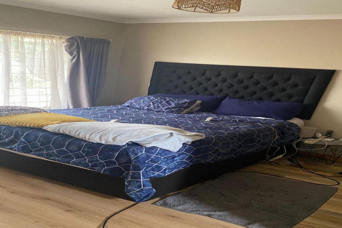 A bedroom featuring laminate flooring and neutral wall tones, providing a functional space with natural light access through the window.
