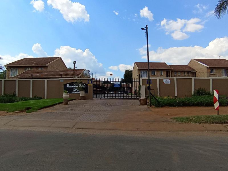 Front entrance view of Ronelda Park apartment complex, featuring a secure gated access point, perimeter walling, and paved driveway.