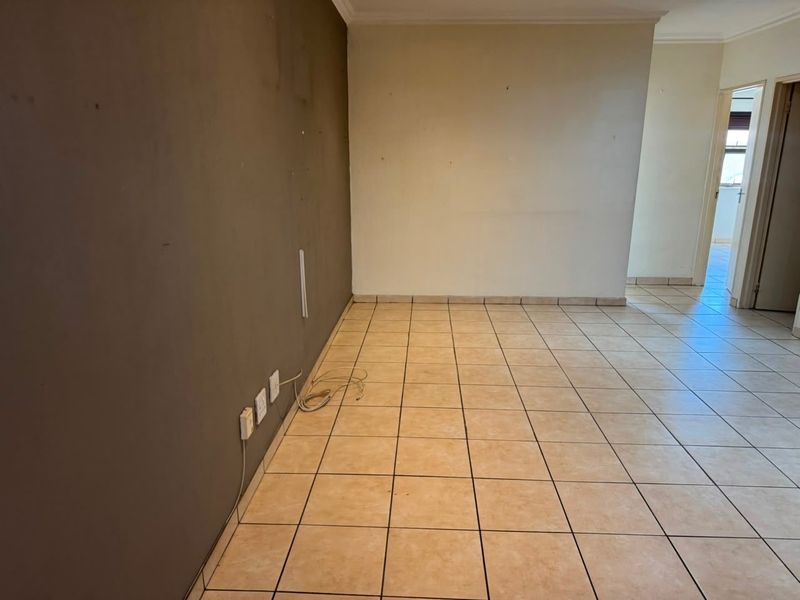 An empty living area featuring neutral tiled flooring and dual-tone painted walls, providing a blank canvas for interior design.
