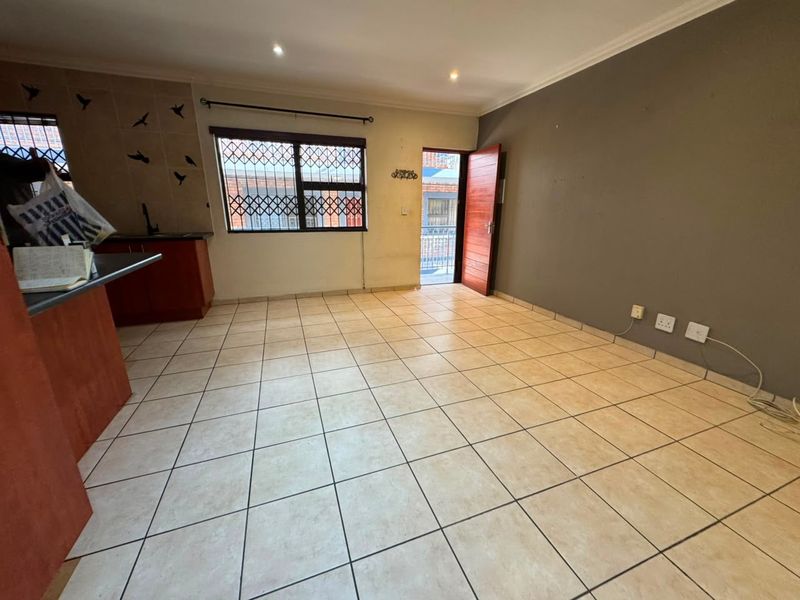 Open-plan living area featuring tiled flooring, recessed lighting, and an integrated kitchen space with direct access to an exterior balcony.