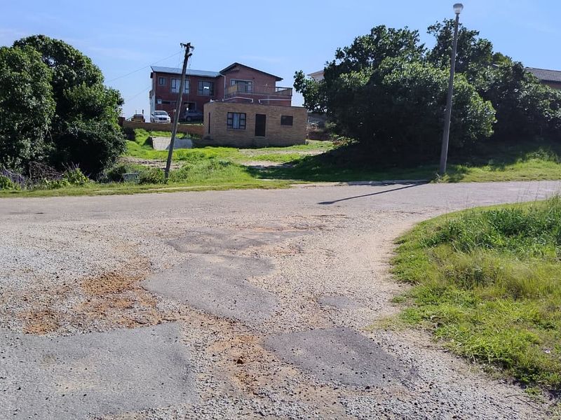 A street view showing the approach to the residential property, featuring an asphalt road with visible surface wear and utility infrastructure.