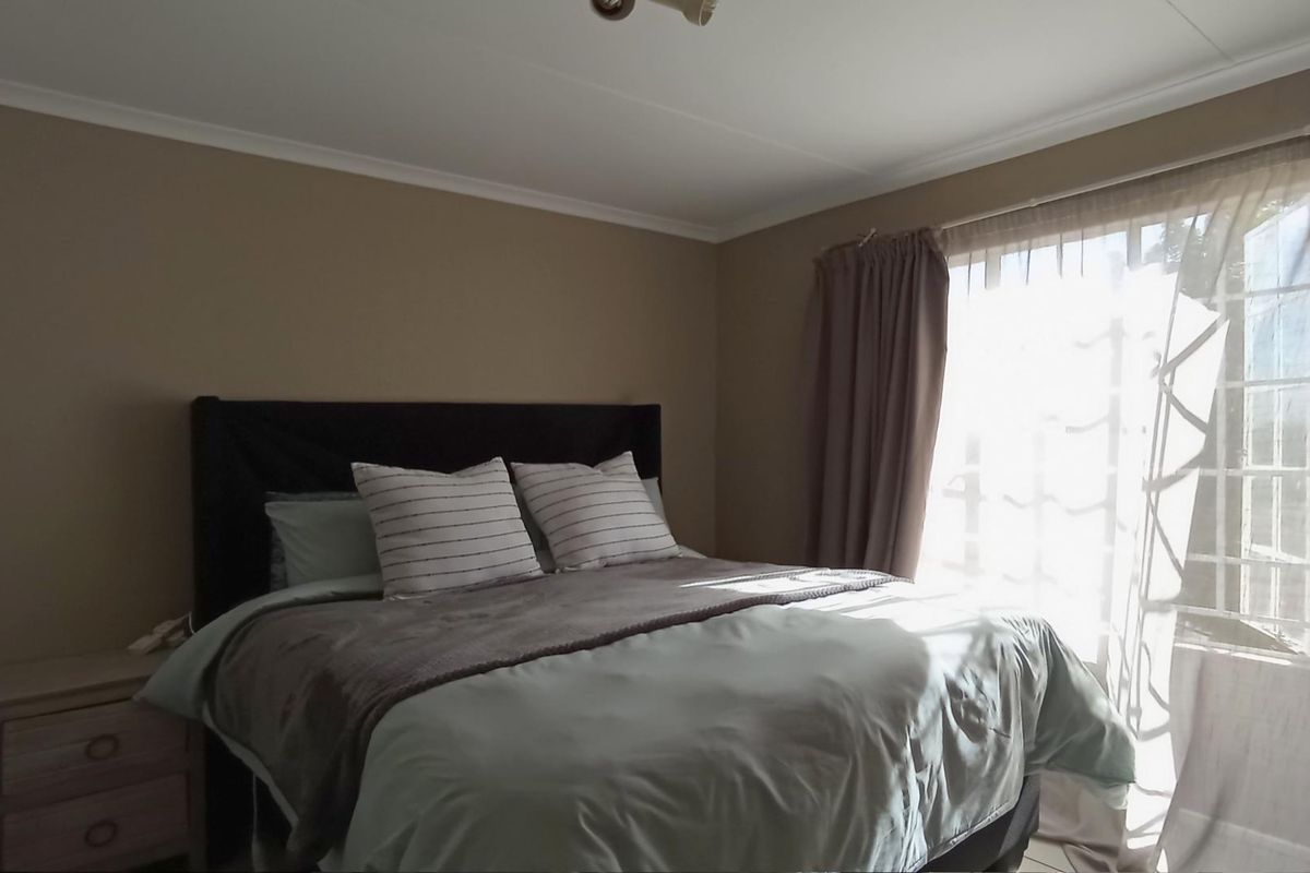 A bedroom featuring neutral wall tones and a window with natural light, providing a comfortable and functional sleeping space.