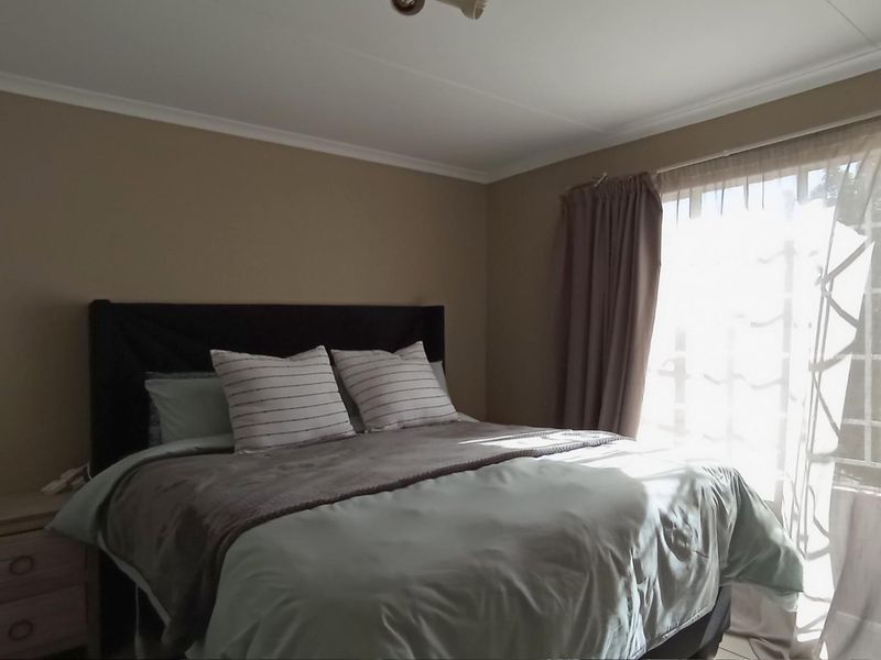 A bedroom featuring neutral wall tones and a window with natural light, providing a comfortable and functional sleeping space.