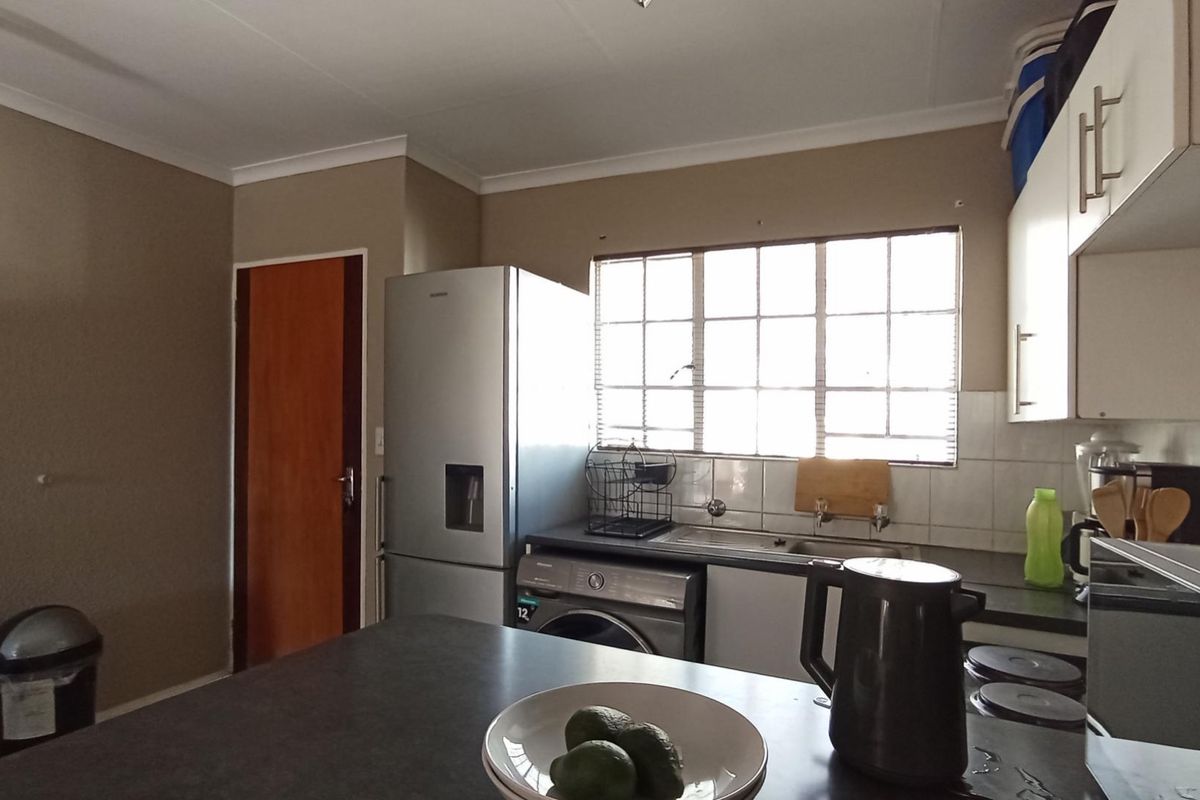 Functional kitchen featuring built-in cabinetry, tiled backsplash, and a stainless steel sink, offering a practical layout for daily meal preparation.