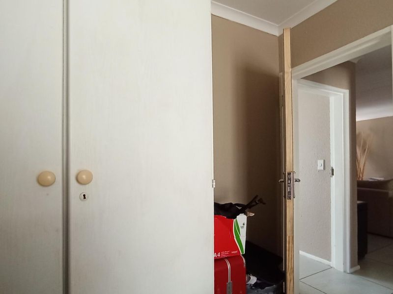 A bedroom interior featuring a built-in wardrobe and an unfinished door frame leading to an adjacent living area.