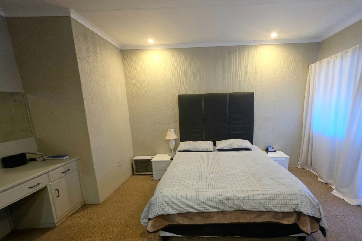 A functional bedroom featuring a built-in vanity, recessed lighting, and neutral textured walls, offering a comfortable space with potential for modern updates.