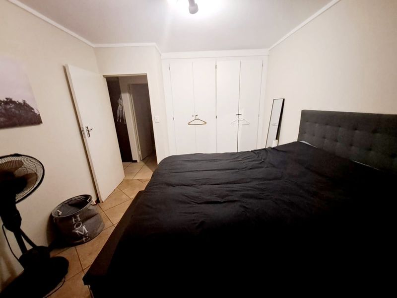 A functional bedroom featuring built-in cupboards and tiled flooring, providing a neutral base for personalization.