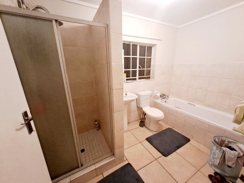 A functional bathroom featuring a separate shower enclosure, bathtub, pedestal basin, and toilet with neutral tiled finishes.
