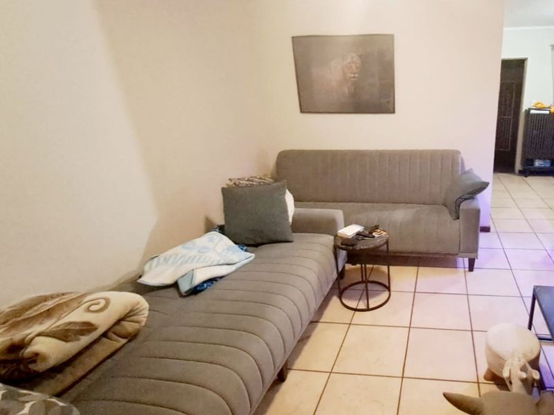 A living room area featuring ceramic floor tiles and a ceiling fan, providing a functional and neutral space.