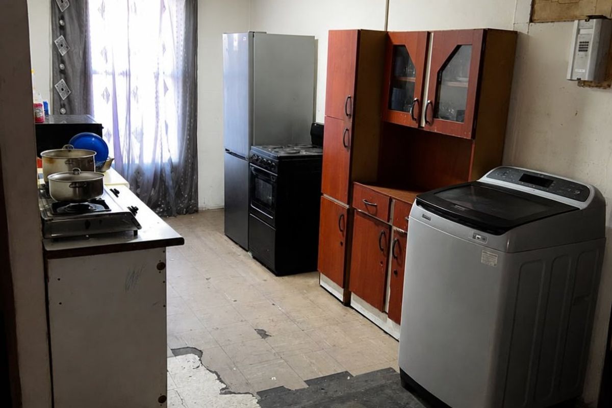 A dated kitchen area featuring original cabinetry, a stove, and worn flooring, offering significant potential for renovation and modernization.