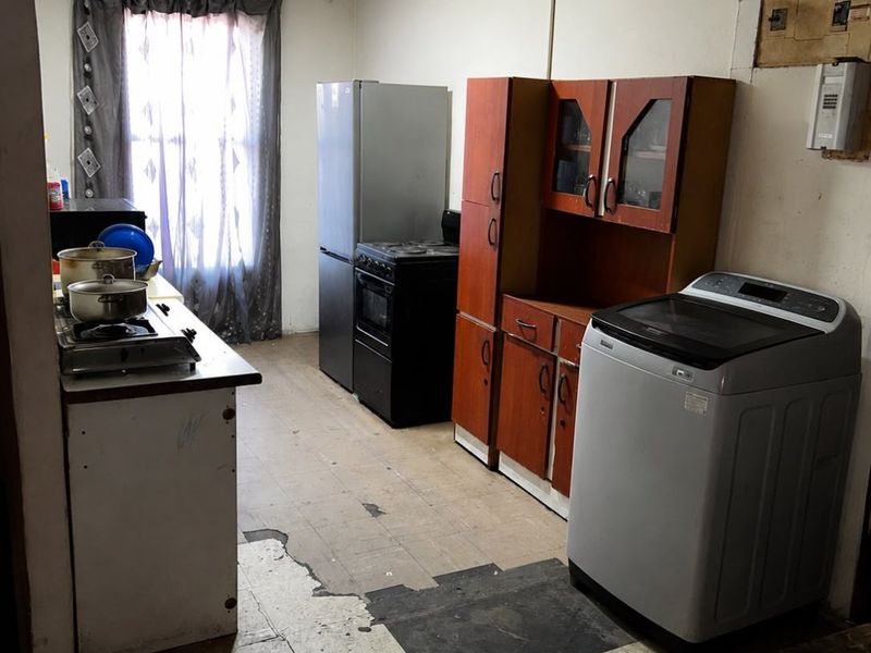 A dated kitchen area featuring original cabinetry, a stove, and worn flooring, offering significant potential for renovation and modernization.