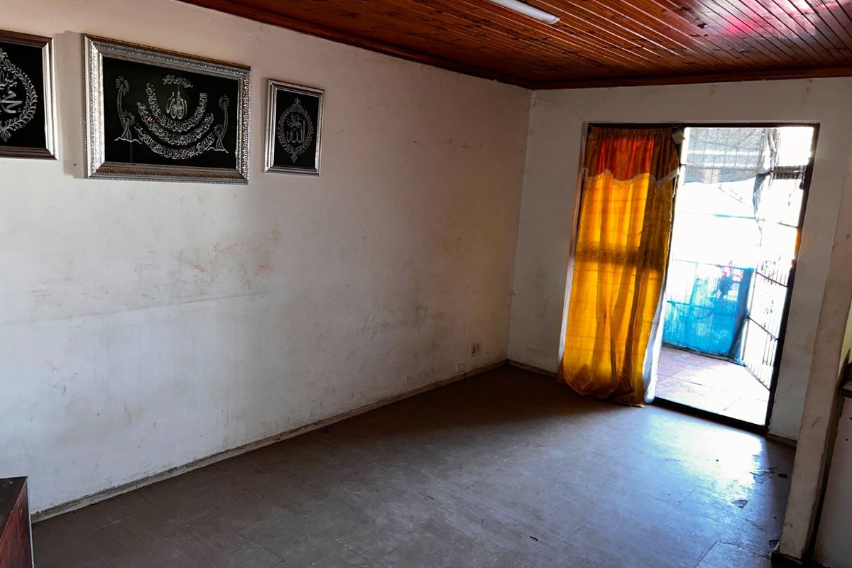 An empty living room featuring a timber ceiling, vinyl flooring, and a sliding glass door leading to an outdoor area.