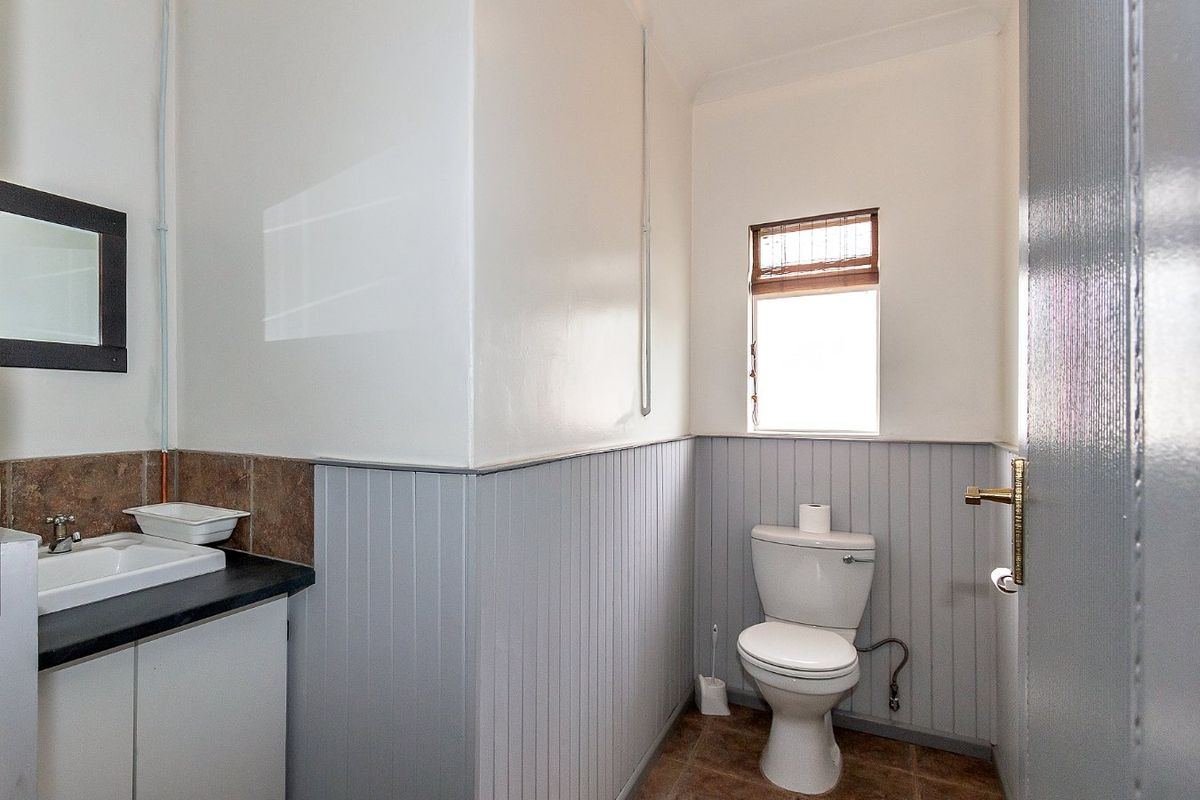 A functional bathroom featuring a vanity cabinet with a basin, a toilet, and classic wainscoting wall paneling.