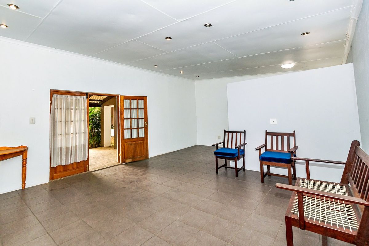 Spacious living area featuring tiled flooring, recessed downlighting, and direct access to an outdoor patio through timber-framed glass doors.