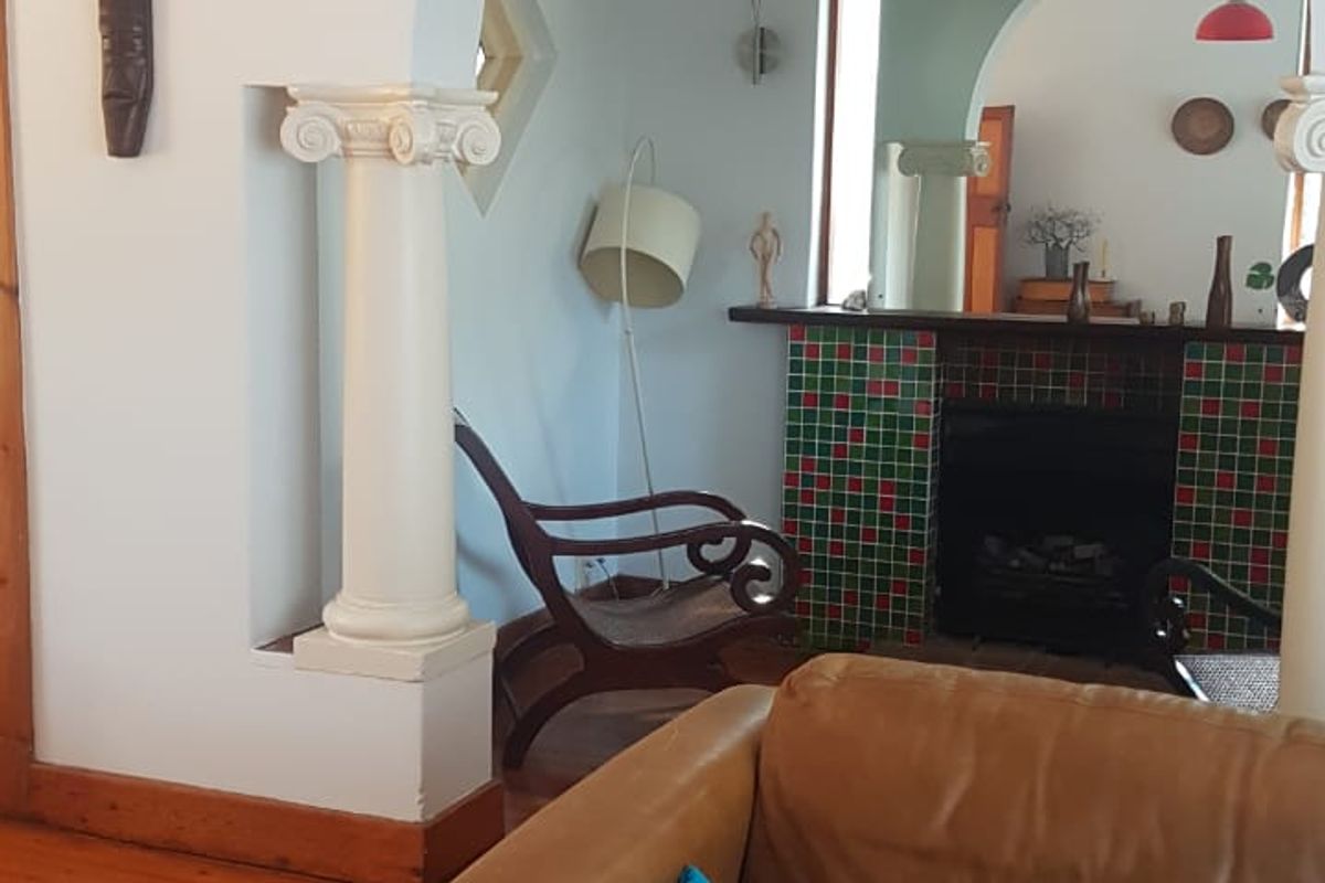 A living room featuring an arched entryway with decorative columns, timber flooring, and a tiled fireplace, showcasing classic architectural character.
