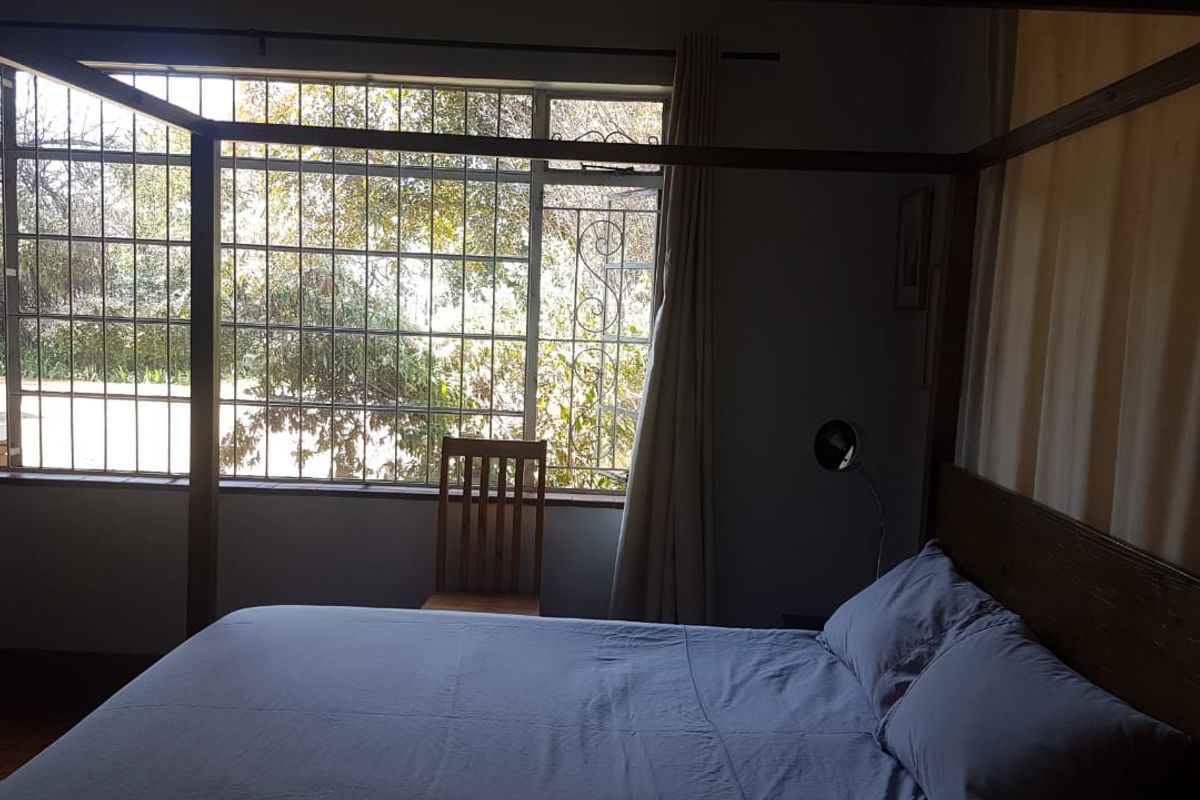 A bedroom featuring a large window with security bars, allowing natural light into the space.