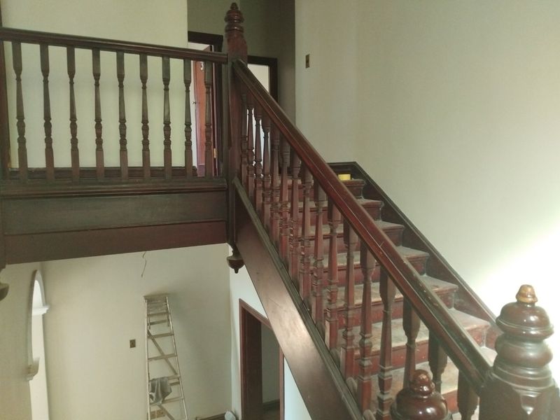 A traditional wooden staircase with a classic balustrade and handrail, showing signs of wear and requiring cosmetic refurbishment.