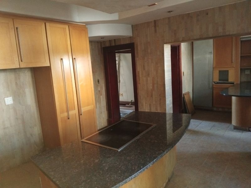 Spacious kitchen featuring a central island with a built-in hob, stone countertops, and extensive wooden cabinetry, offering a functional layout for renovation.