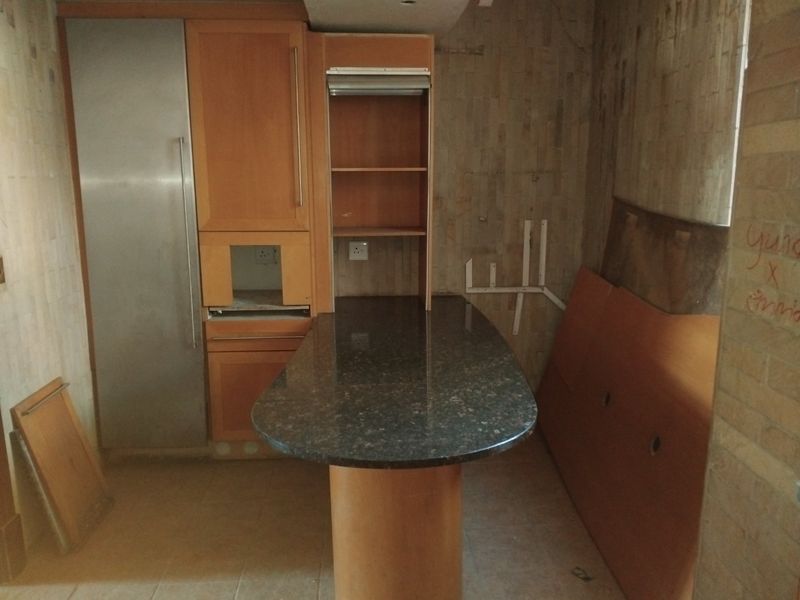 A kitchen space featuring granite countertops and built-in cabinetry, currently in a state of partial disassembly and requiring renovation.