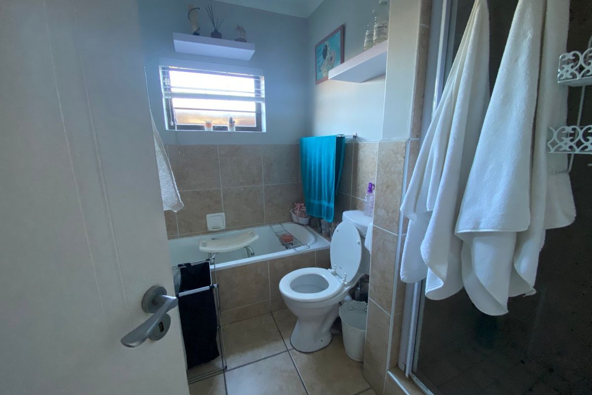 A functional bathroom featuring a bathtub, toilet, and separate shower enclosure with neutral tiled finishes.