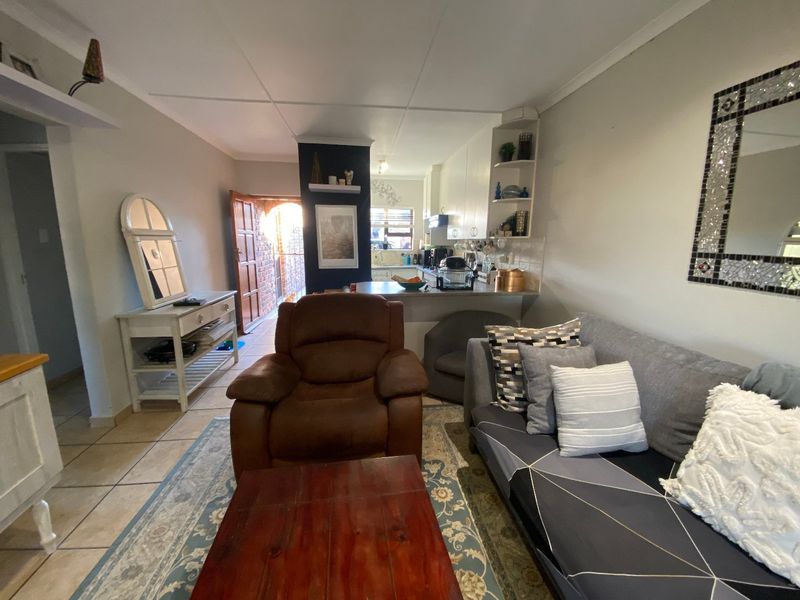 Open plan living area featuring a breakfast counter and adjoining kitchen with built-in cabinetry and tiled flooring.