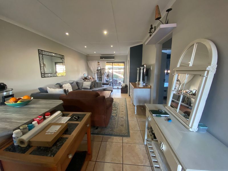 Open-plan living area featuring tiled flooring, recessed downlighting, and a split-system air conditioner, with direct access to an outdoor patio through sliding glass doors.