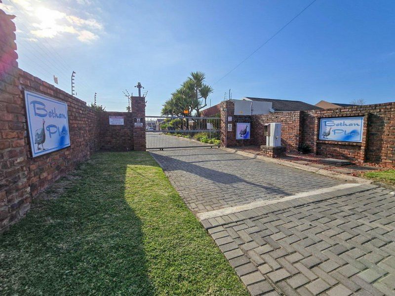 Front entrance view of the residential complex featuring a brick boundary wall, paved driveway, and secure gated access.