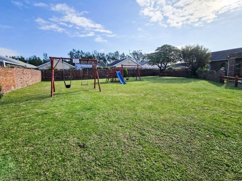 A spacious, level backyard featuring a well-maintained lawn enclosed by solid brick boundary walls.