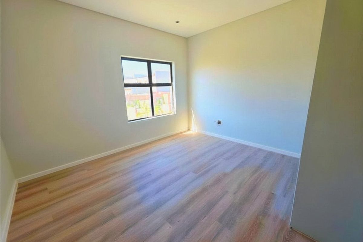A bright, empty bedroom featuring modern laminate flooring and a clean, neutral aesthetic, ready for personalization.