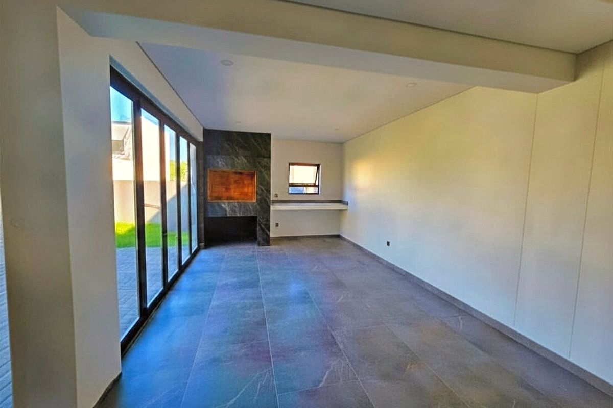 Spacious living area featuring large format floor tiles, a modern stone-clad built-in fireplace, and expansive sliding glass doors opening to the exterior.