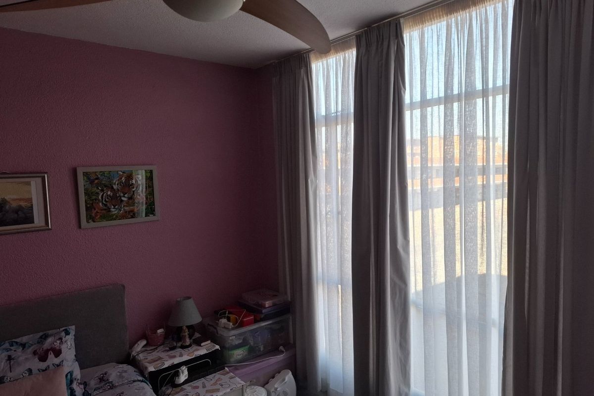 A bedroom featuring a ceiling fan and large windows that provide natural light.