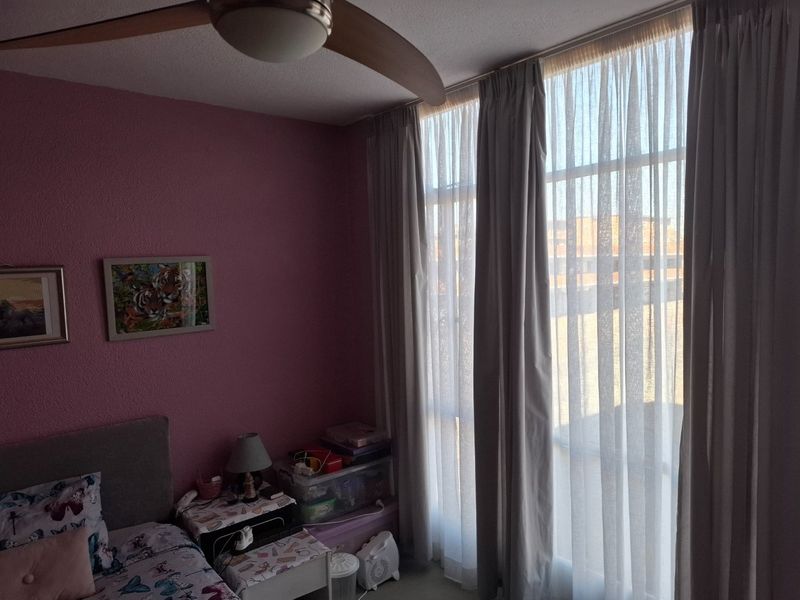 A bedroom featuring a ceiling fan and large windows that provide natural light.