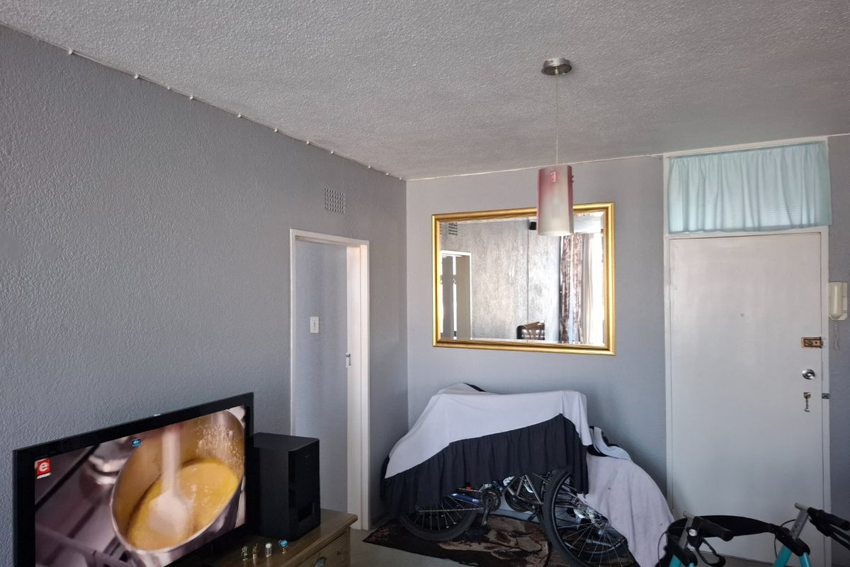 A living room area featuring grey painted walls, a central pendant light fixture, and an integrated intercom system near the entrance door.