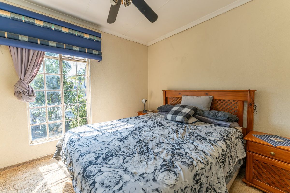 A cozy bedroom featuring a ceiling fan and a large grid-pattern window that allows for natural light.