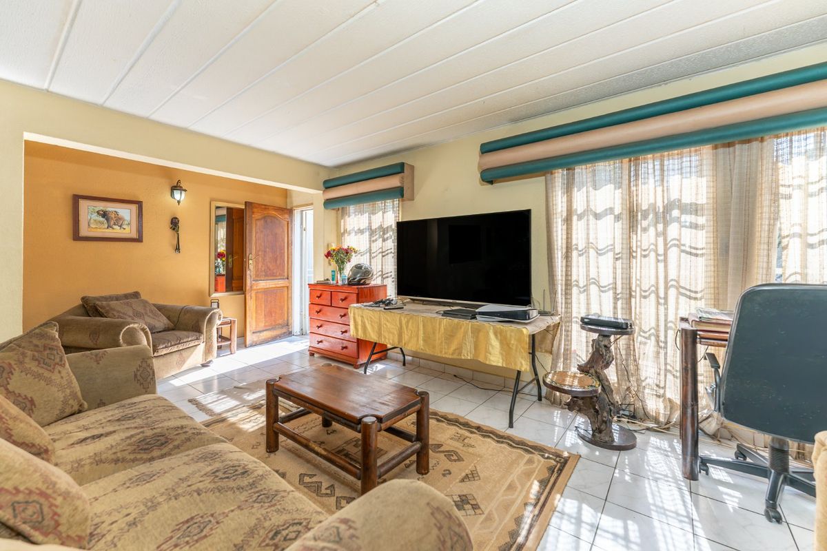A living room featuring tiled flooring, a panelled ceiling, and access to an outdoor area through a sliding glass door.