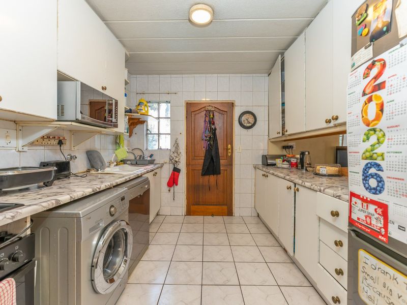 A functional galley-style kitchen featuring tiled flooring, laminate countertops, and ample built-in cabinetry, offering a practical layout for daily meal preparation.