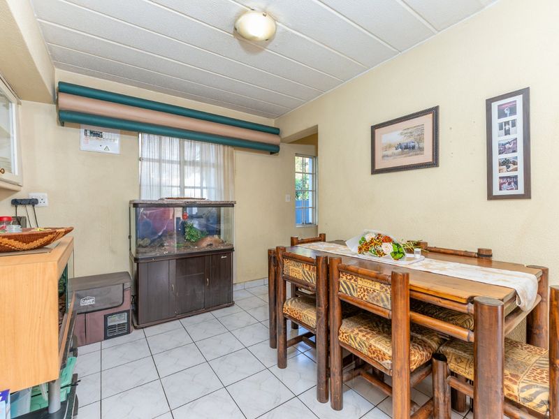 A dining area featuring tiled flooring and a drop ceiling, offering a functional space for meals with direct access to adjacent areas.